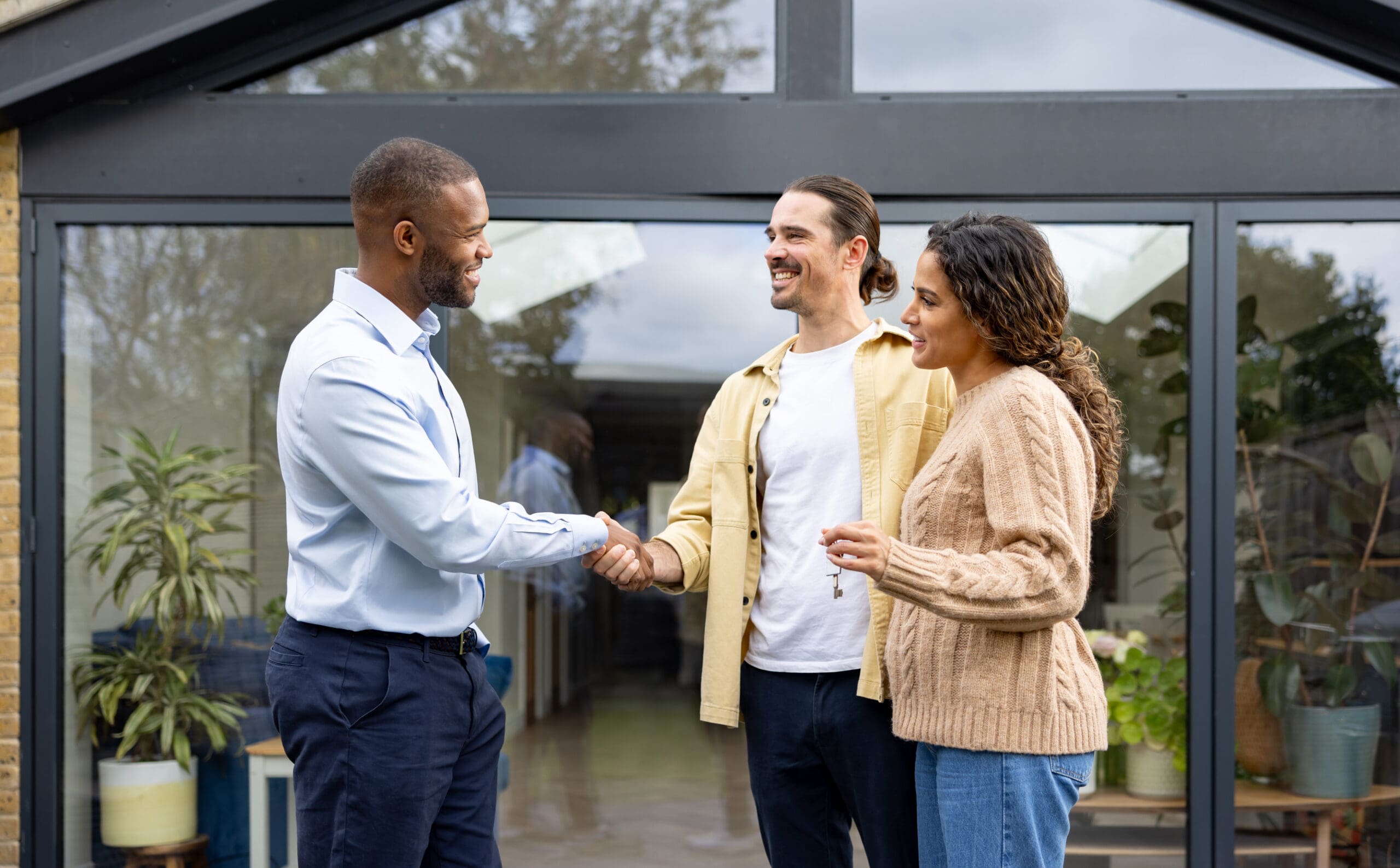 Real estate agent greeting couple at house